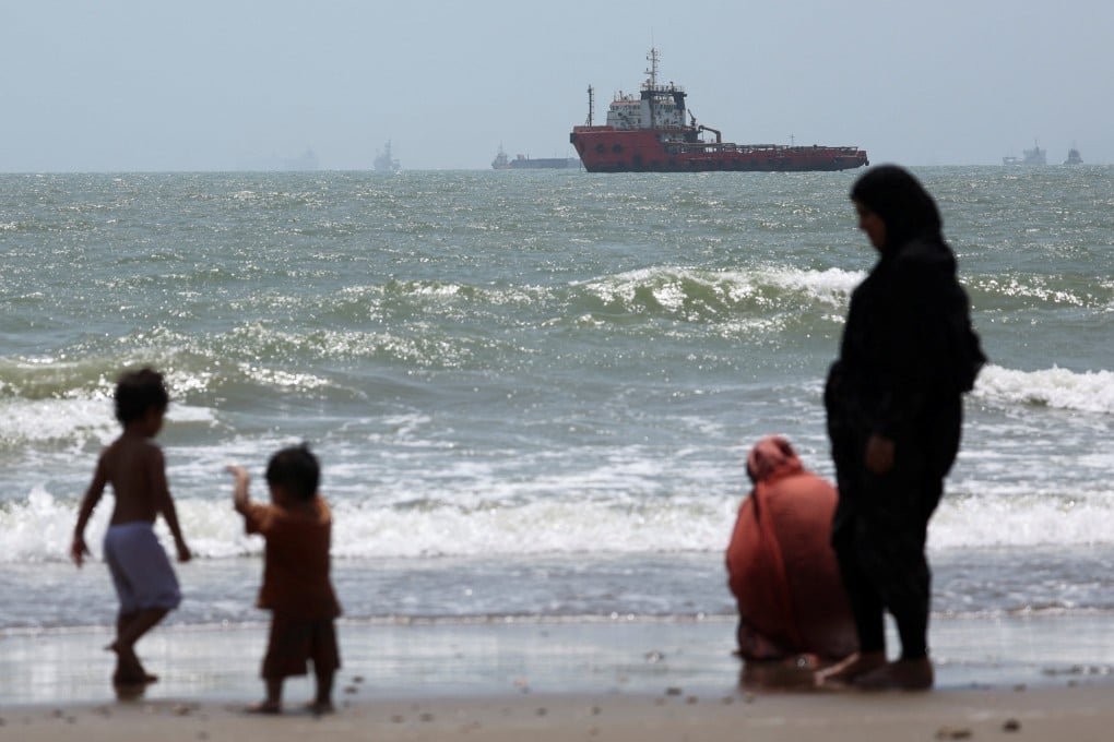 People gather as stranded vessels in the Strait of Hormuz are visible near the beach of Bandar Abbas in Iran on August 25. Photo: Reuters