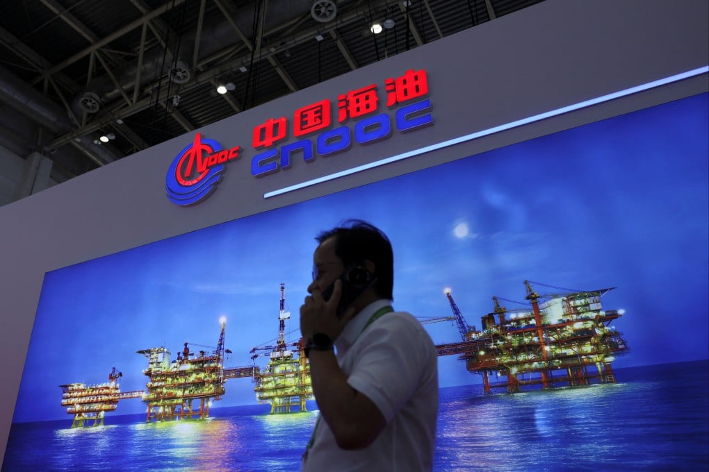 A man uses his mobile phone as he walks past the booth for the China National Offshore Oil Corporation at an expo in Beijing. Photo: Reuters