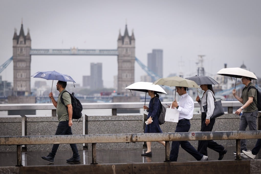 Commuters cross London Bridge during heavy rainfall in Britain on Thursday. Photo: EPA