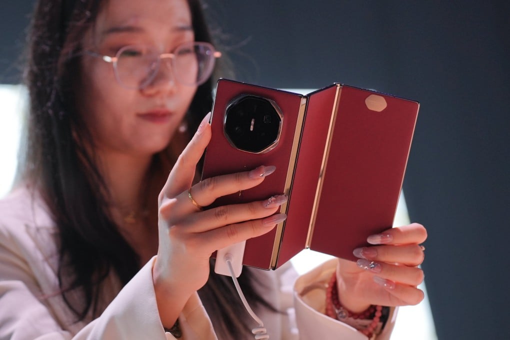 A Huawei staff member holds a Mate XT tri-fold smartphone during a product launch event last year. The Chinese tech giant unveiled the Huawei Mate XT, the world’s first tri-fold smartphone, for its international market. Photo: EPA-EFE