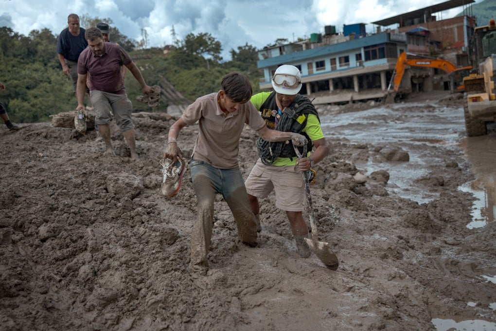 A rescuer helps a resident through heavy mud following flash floods in Trishuli, Nepal. Photo: Getty Images/TNS