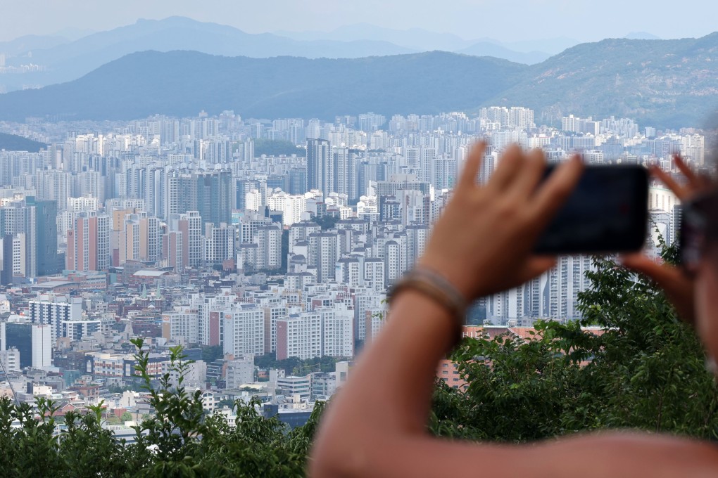 A woman takes a photo of residential complexes in Seoul on August 23. Photo: Yonhap/EPA
