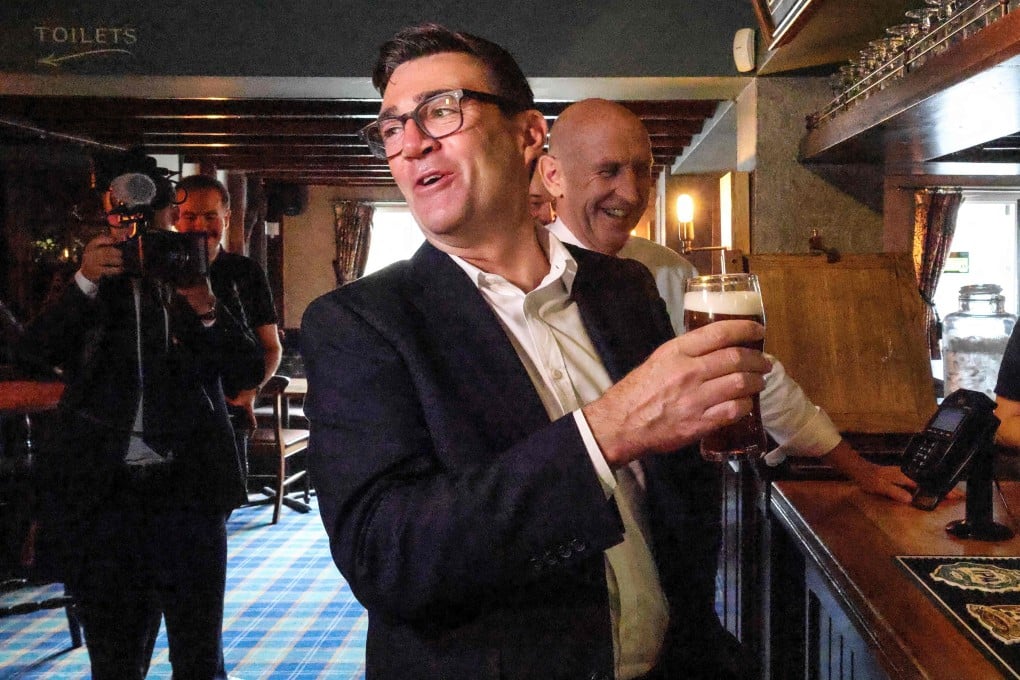 Britain’s Prime Minister Andy Burnham holds a pint of beer during a visit to the Hare Inn in Harlow, east of London with the Chancellor John Healy (centre) on July 23. Photo: AFP
