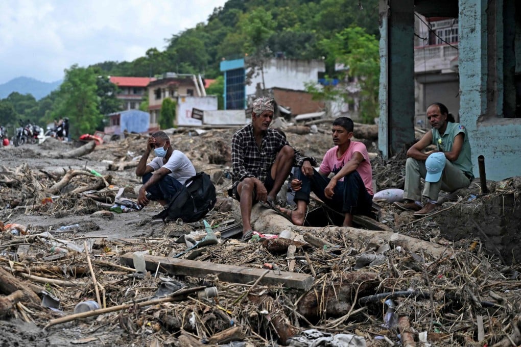 Residents sit beside debris as they salvage belongings following flash floods at Devighat in Nepal’s Nuwakot district on August 31. Photo: AFP