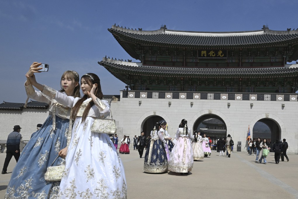 Visitors wearing traditional hanbok dresses take a selfie in front of Gwanghwamun Gate, the main gate of Gyeongbokgung, a former royal palace in Seoul, on March 16, 2026. Photo: AFP