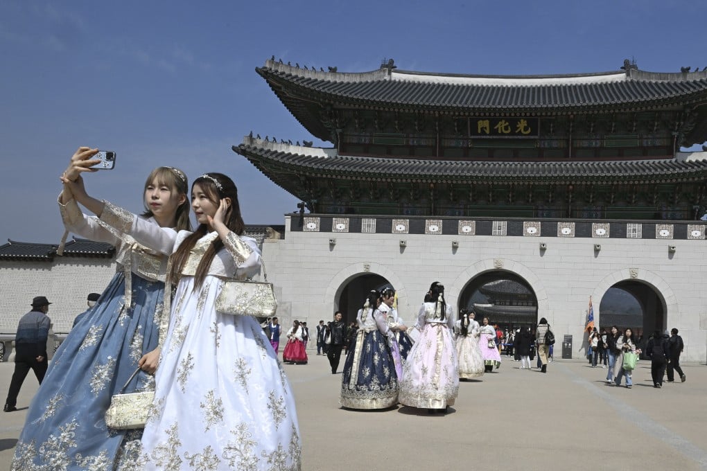Visitors wearing traditional hanbok dresses take a selfie in front of Gwanghwamun Gate, the main gate of Gyeongbokgung, a former royal palace in Seoul, on March 16, 2026. Photo: AFP