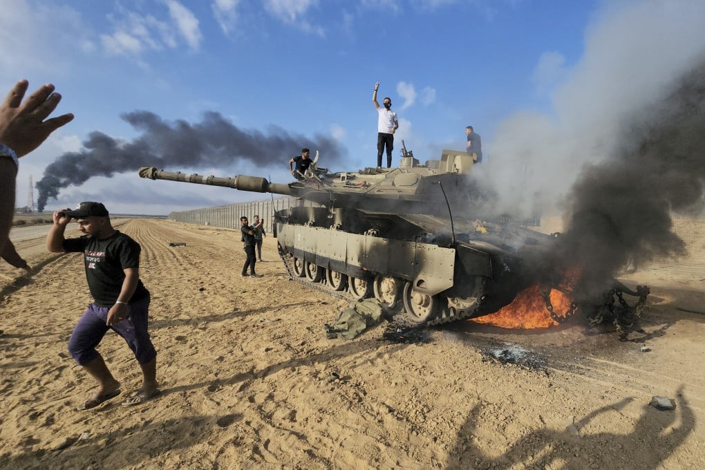 Palestinians celebrate by a destroyed Israeli tank at the Gaza Strip fence on October 7, 2023. Photo: AP