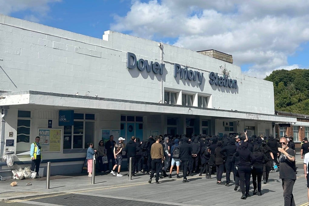 Black-clad and masked demonstrators gather at a train station after blocking roads in the UK port town of Dover. Photo: via dpa