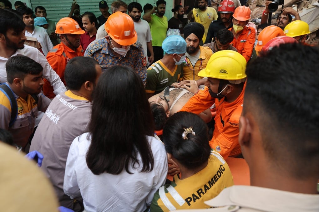 Rescuers carry a survivor from the rubble of a collapsed building in New Delhi on Sunday. Photo: EPA