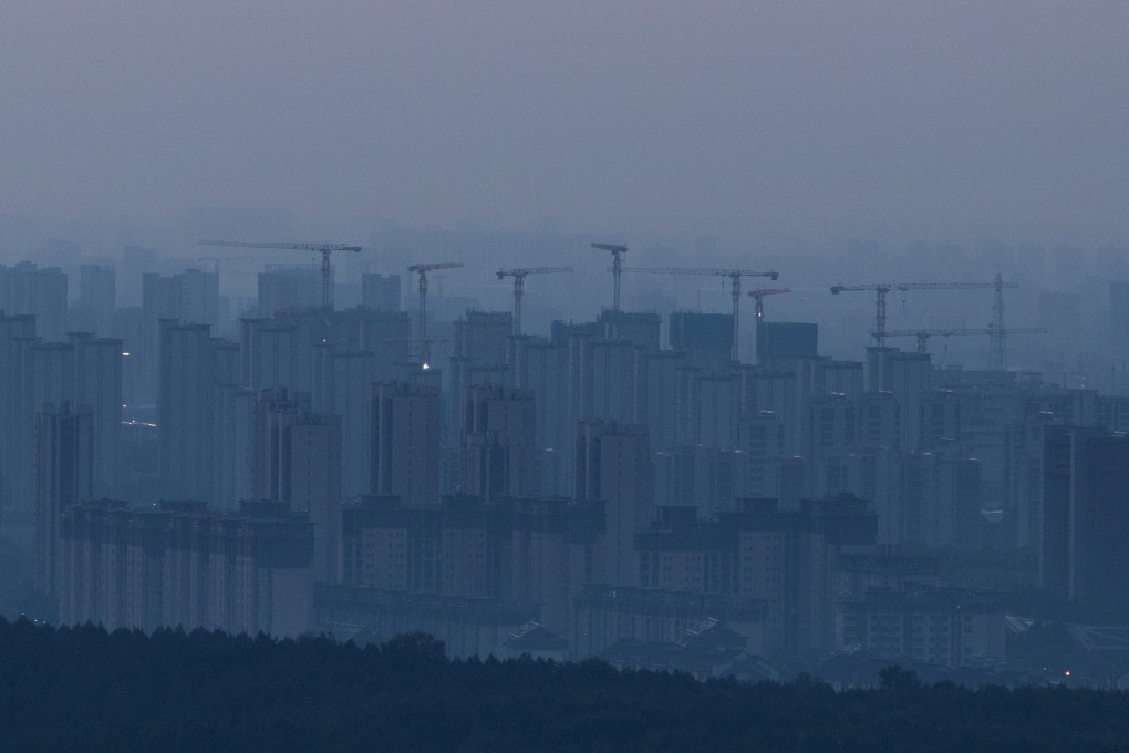 Construction cranes rise above a newly built residential district before sunrise in Beijing on September 3. Photo: Reuters