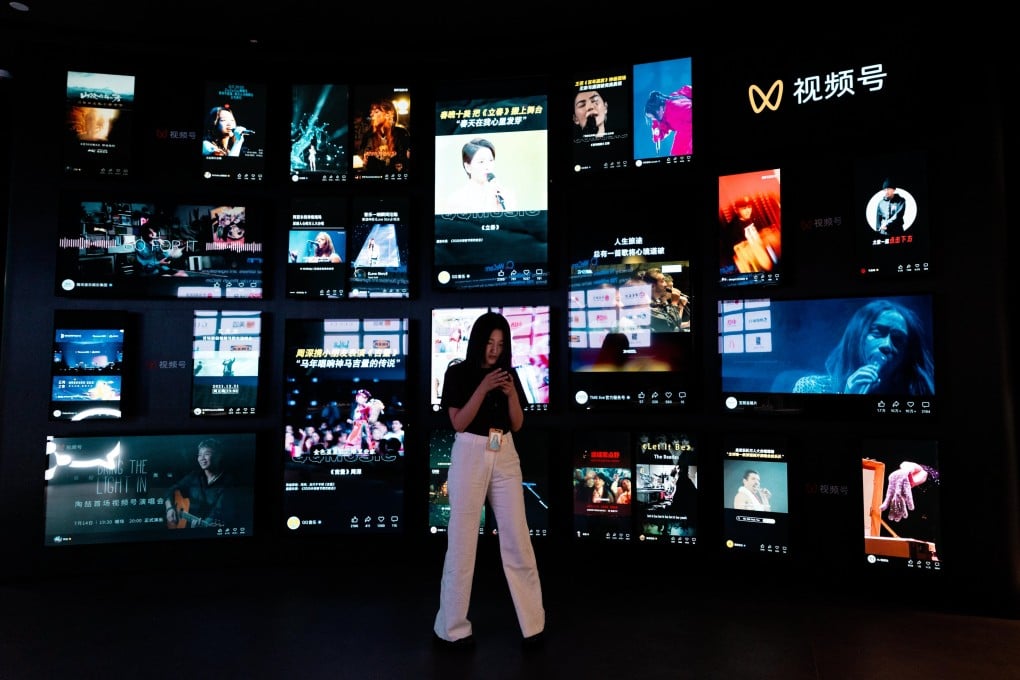 A woman uses her phone in front of a video wall in Tencent headquarters in Shenzhen on April 17, 2026. Photo: EPA
