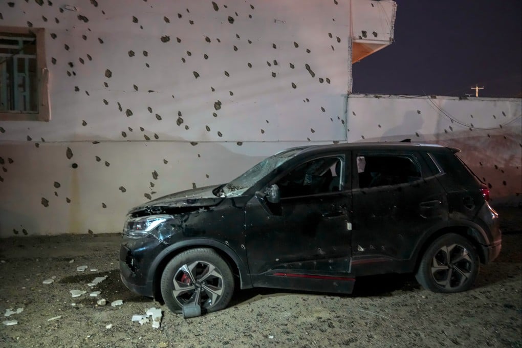 A damaged car beside a wall bearing numerous impact marks near the site of a strike in Lamerd, southern Iran, on February 28. Photo: Tasnim News Agency via AP