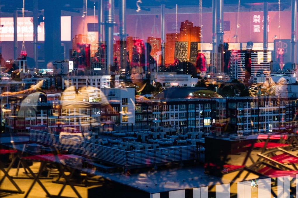 Cooling facilities are seen on the roof of a data centre building (bottom centre) as people at a restaurant are reflected on a pane of glass in Bangkok, Thailand. Photo: AFP