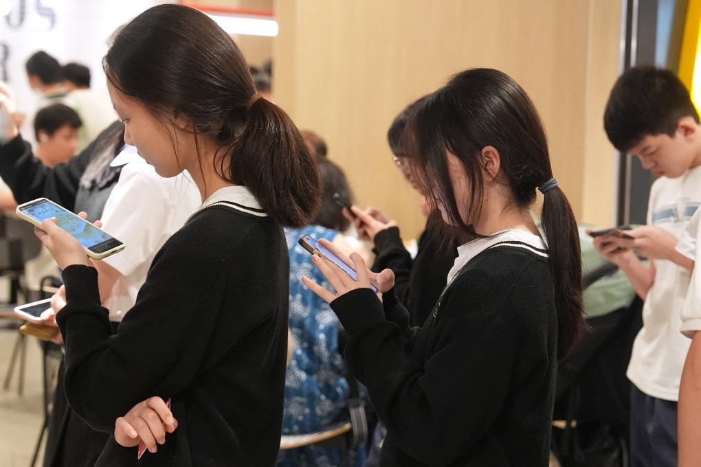 Students use their smartphones while queuing outside a restaurant in Tseung Kwan O on October 16,2025. Photo:  Elson Li