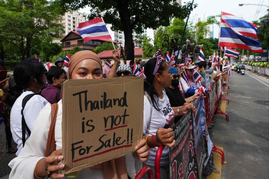 Protesters holding signs attend a rally demanding an end to alleged land-grabbing by foreigners in Bangkok on Thursday. Photo: AP