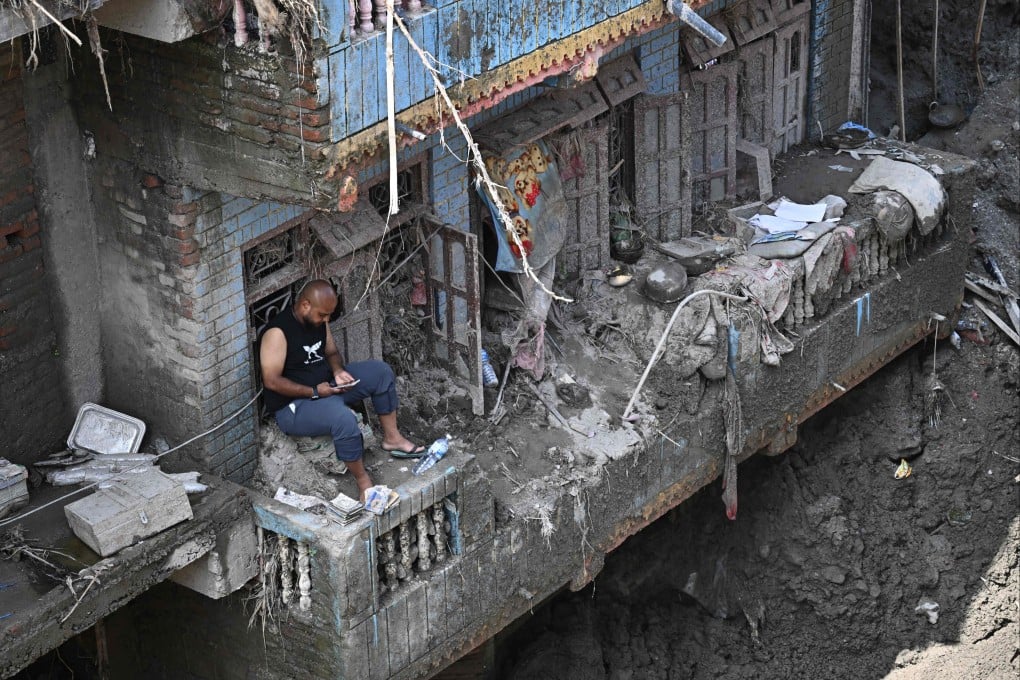A man sits on the balcony of a sludge-ridden house in Nepal’s Nuwakot district on September 8. The August 26 glacial and mountain collapse on the China-Nepal border killed at least 1,398 people, with more than 5,500 missing, including around 800 foreigners. Photo: AFP
