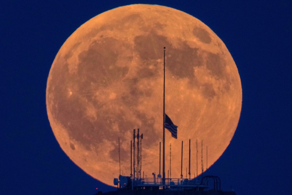 A full moon rises beyond an American flag. Photo: AP
