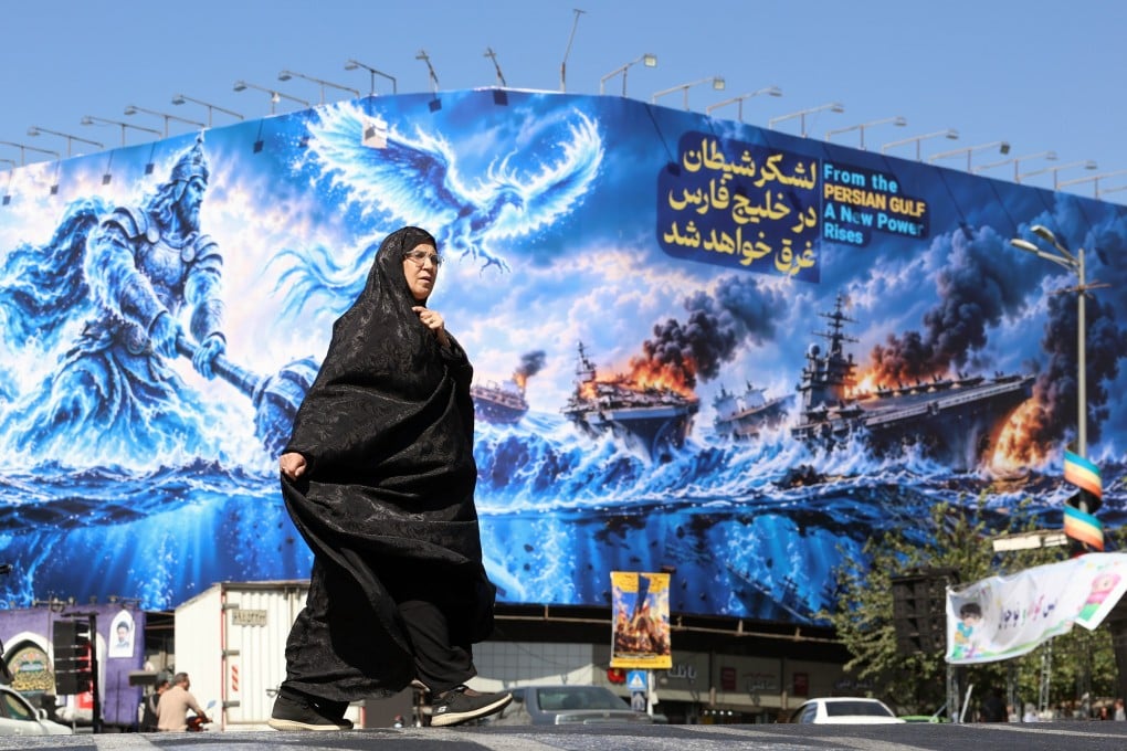 An Iranian woman walks next to an anti-US billboard in Tehran on Monday. Photo: EPA