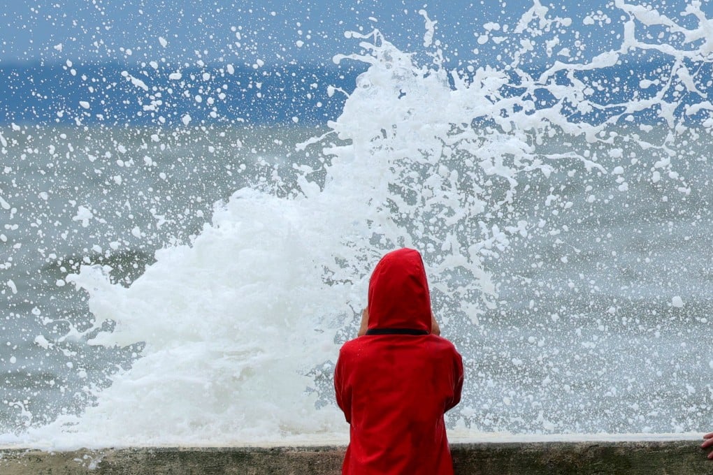 A person takes pictures as waves crash into a seawall on Long Island Sound in Rye, New York, on Saturday. Photo: Reuters