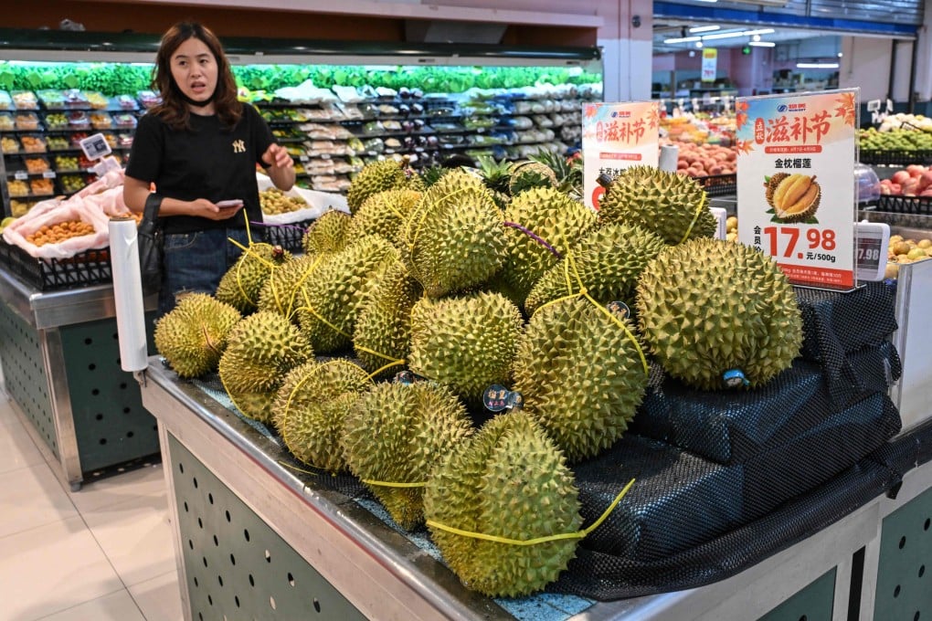A woman checks out imported Thai durians at a supermarket in Beijing in August. Photo: AFP