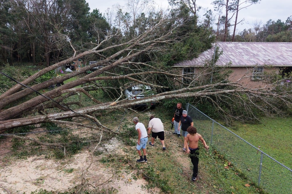 A group of residents cuts downed trees in front of a home in Milton, Florida, on Saturday. Photo: AP
