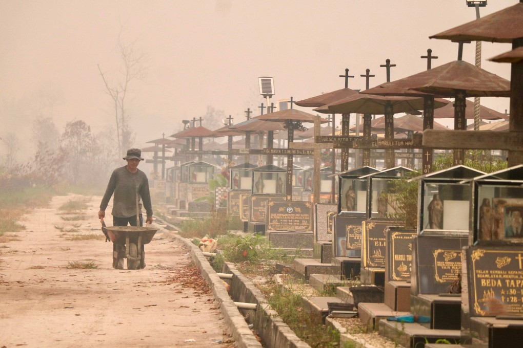 A worker pushes a wheelbarrow through a public cemetery blanketed in thick smoke haze caused by forest and land fires in Palangka Raya, Indonesia, on September 30, 2026. Photo: AFP