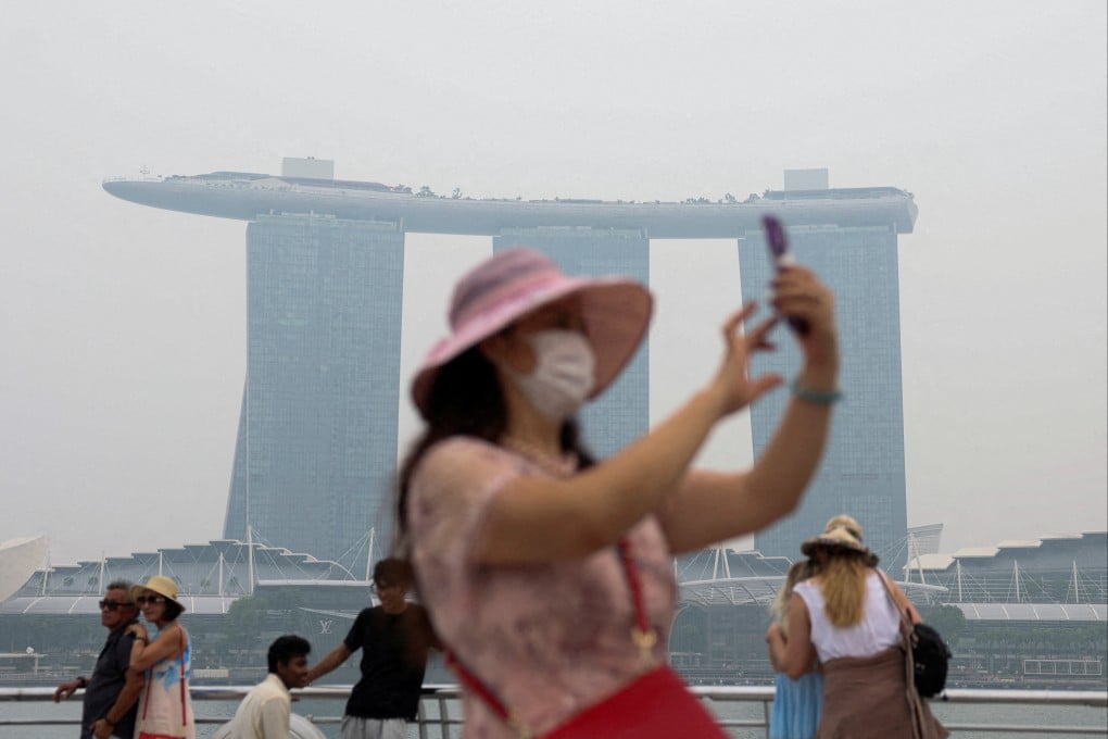 A tourist wears a face mask as haze covers Singapore’s Merlion Park and Marina Bay Sands on Friday. Photo: Reuters