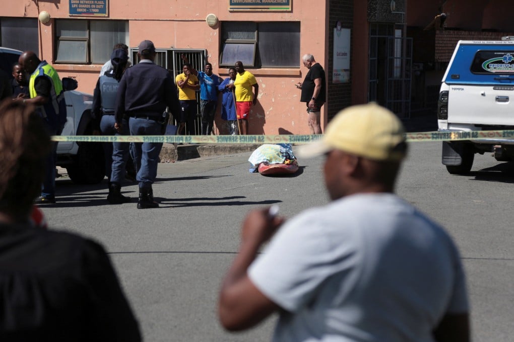Police officers stand guard as bystanders gather near the covered body of a woman who was killed in a shark attack while swimming off Orient Beach in KuGompo City, Eastern Cape, South Africa, on Tuesday. Photo: Reuters