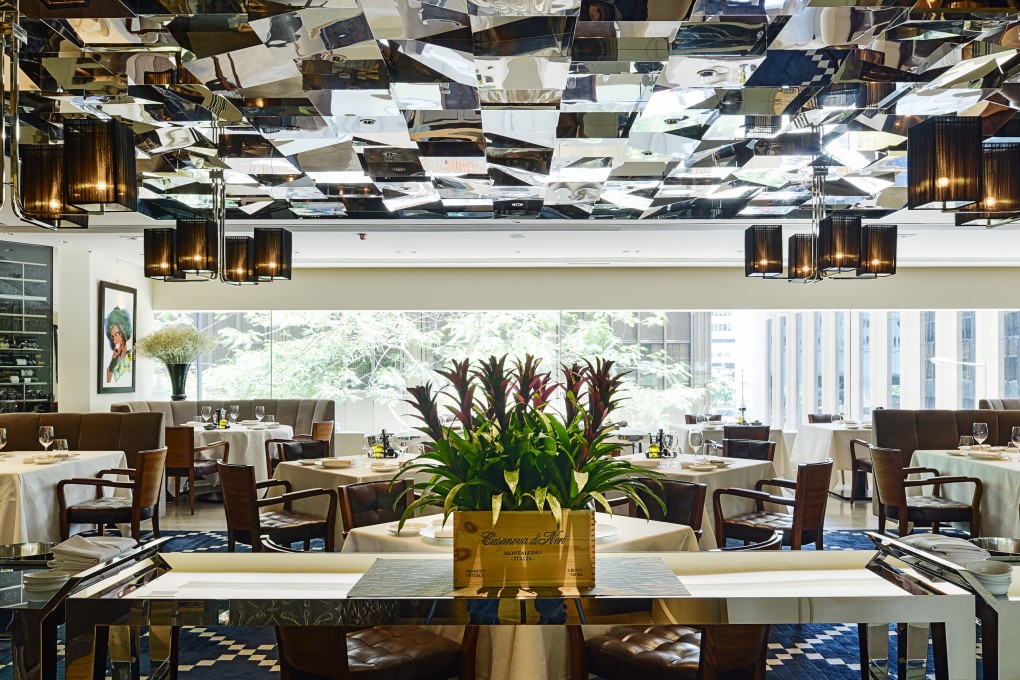 The interior at 8 1/2 Otto e mezzo Bombana is contemporary chic, with a mirrored ceiling, banquette seating with nooks for privacy, and chandeliers.