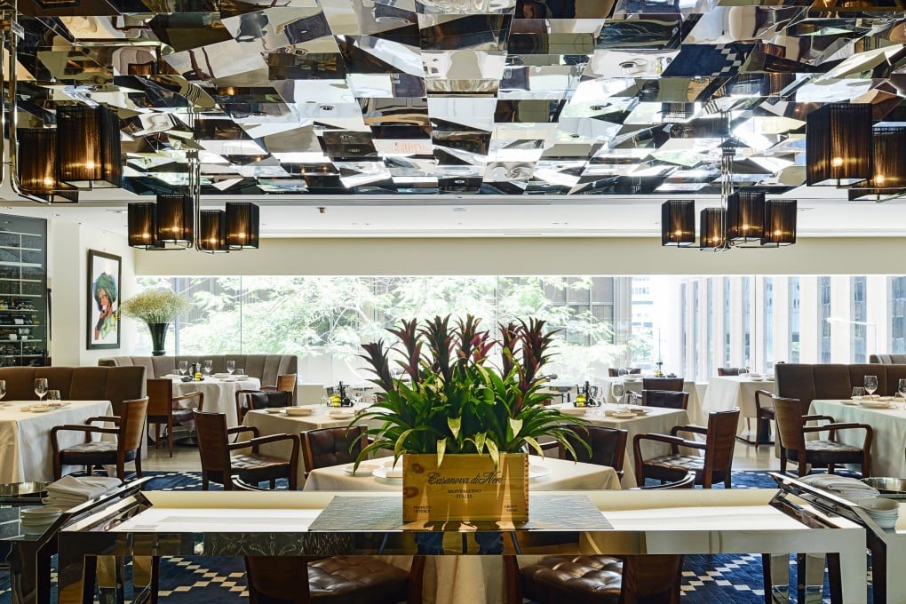 The interior at 8 1/2 Otto e mezzo Bombana is contemporary chic, with a mirrored ceiling, banquette seating with nooks for privacy, and chandeliers.