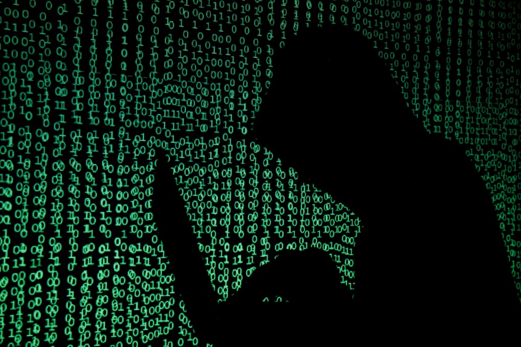 A hooded man holds a laptop computer as cyber code is projected on him in this illustration picture. Photo: Reuters