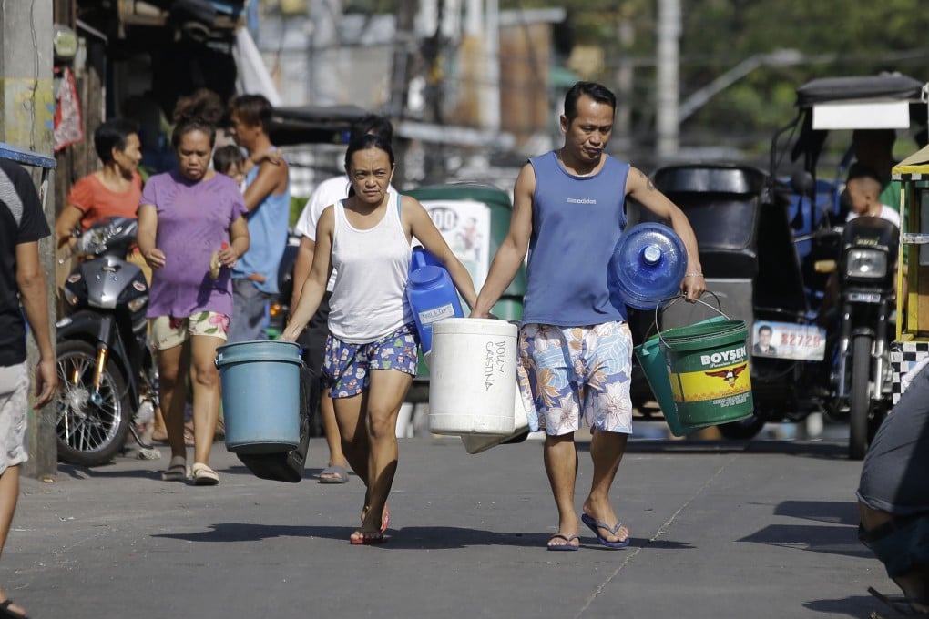 A couple carries empty containers looking for places to collect water in Mandaluyong, metropolitan Manila. Photo: AP
