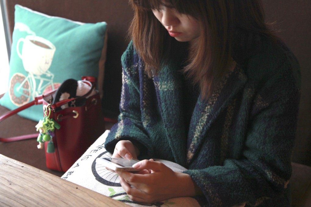A woman checks her phone at a cafe in Beijing, China. photo: Reuters
