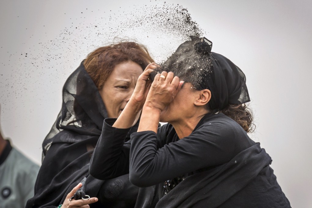 A relative of a crash victim throws dirt in her own face after realising that there is nothing physical left of her loved one. Photo: AFP