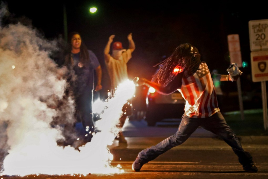 Edward Crawford Jnr returns a tear gas canister fired by police who were trying to disperse protesters in Ferguson. Photo: St. Louis Post-Dispatch via AP