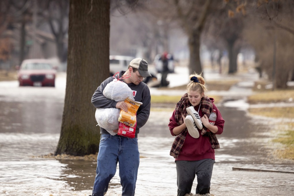 Anthony Thomson, left, and Melody Walton make their way out of a flooded neighbourhood in Fremont. Photo: Omaha World-Herald via AP