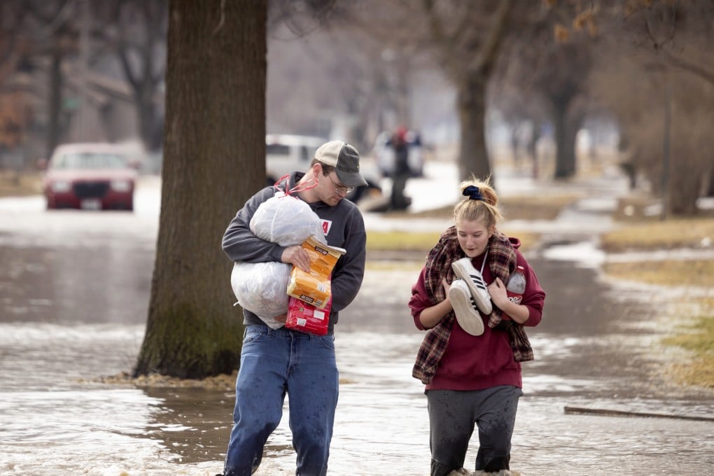 Anthony Thomson, left, and Melody Walton make their way out of a flooded neighbourhood in Fremont. Photo: Omaha World-Herald via AP