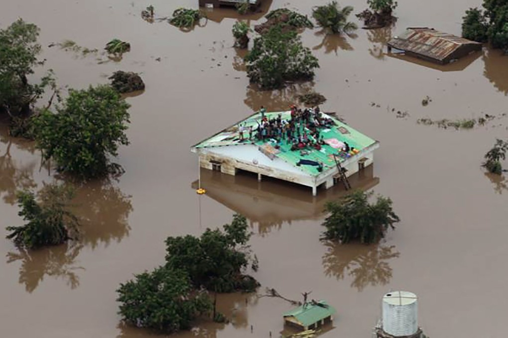 Groups of people stuck on rooftops with floodwaters up to window level in Beira. Photo: AFP