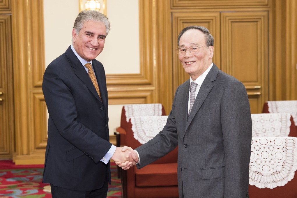 Wang Qishan shakes hands with Makhdoom Shah Mahmood Qureshi in Beijing on Tuesday. Photo: Xinhua