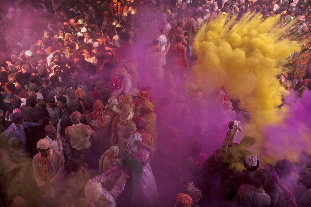 Indians covered in colourful powder as they pray at the Radha Rani Temple in Barsana, India, during ‘Lathmar Holi’, a variation of Holi that includes women playfully beating men with sticks. Photo: AP