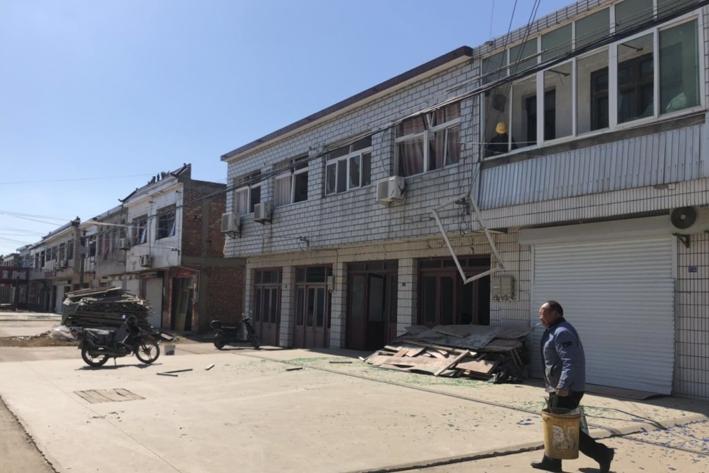 A resident walks through piles of glass from shattered windows near the site of the blast in Yancheng. Photo: Sidney Leng