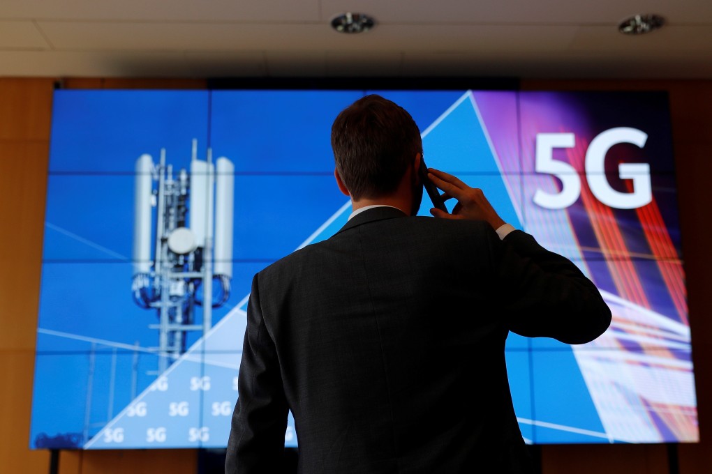An employee of Germany's Federal Network Agency uses his mobile phone in front of a screen set up for the auction of spectrum for 5G services at the Bundesnetzagentur headquarters in Mainz, Germany, March 18, 2019. Photo: Reuters