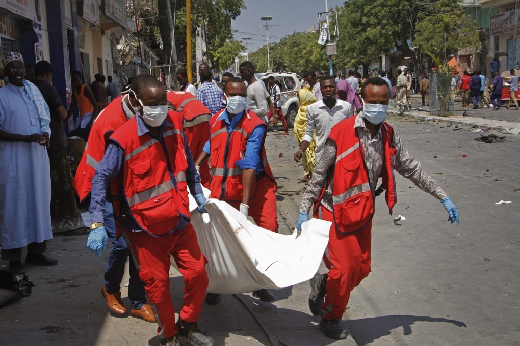 Medics carry away the dead body of a woman killed after a blast outside a restaurant in Mogadishu. Photo: AP Photo