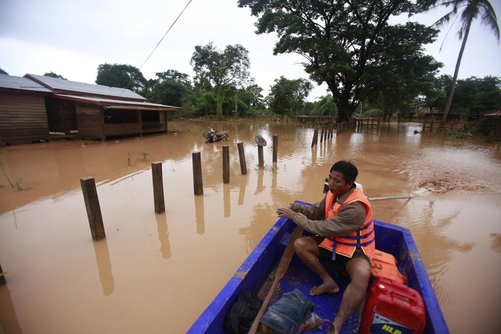 A man paddles his boat through a flooded village after a dam in southeastern Laos collapsed, in the Sanamxay district, Attapeu province, Laos. A United Nations human rights expert is urging Laos to focus less on big, foreign-invested dam and railway contracts. Photo: AP