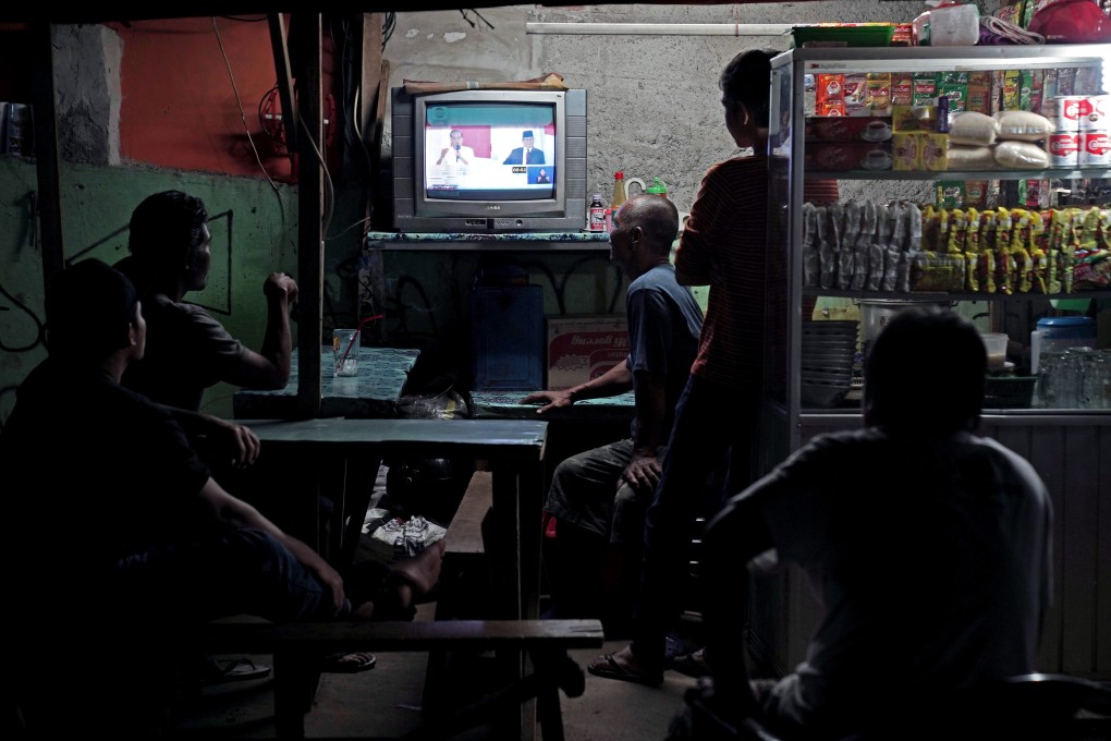 People watching the debate on television at a food stall in Jakarta on March 30, 2019. Photo: Bloomberg