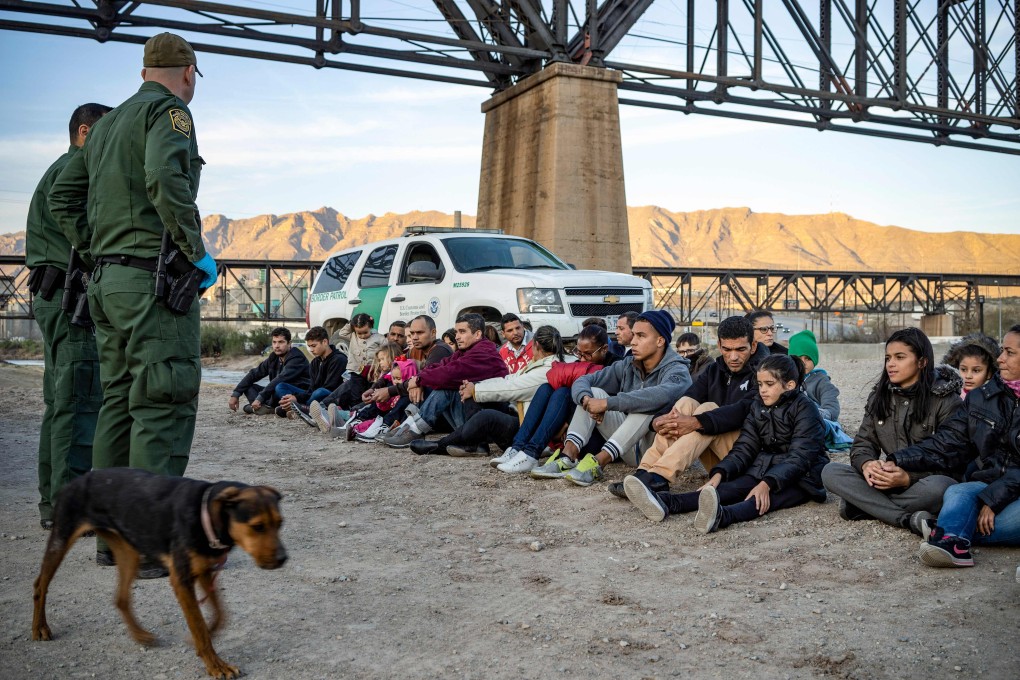 A group of about 30 Brazilian migrants, who had just crossed the US-Mexico border, sit on the ground near US Border Patrol agents, on the property of Jeff Allen in Sunland Park, New Mexico on March 20. Photo: AFP
