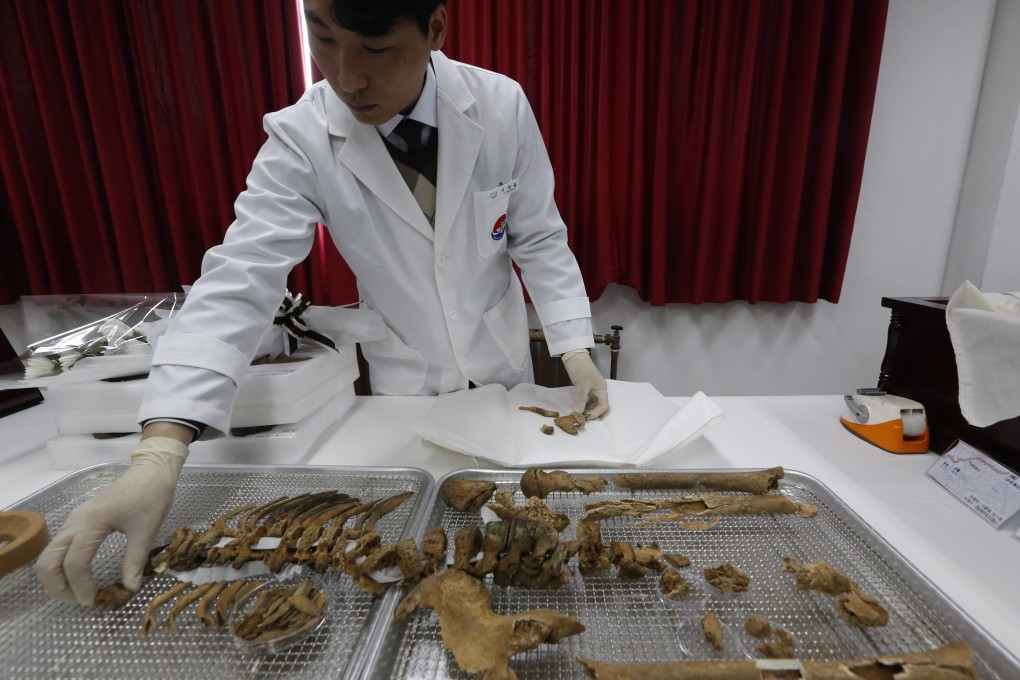 A member of MND Agency for KIA Recovery and Identification of South Korea arranges the remains of Chinese soldiers who were killed in the Korean war. Photo: EPA