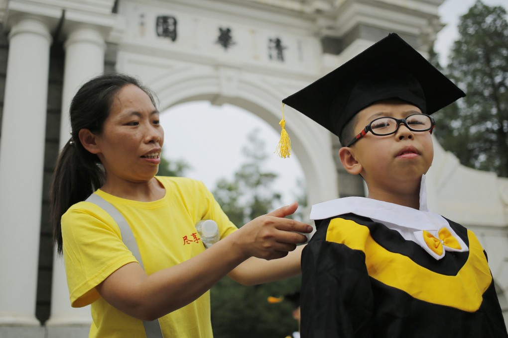 A woman helps a young tourist into academic gown for a photograph at Tsinghua University during summer vacation. Tsinghua is now ranked among the world’s top 10 universities in engineering and technology, and Hong Kong students have a better chance of entering Chinese universities. Photo: EPA