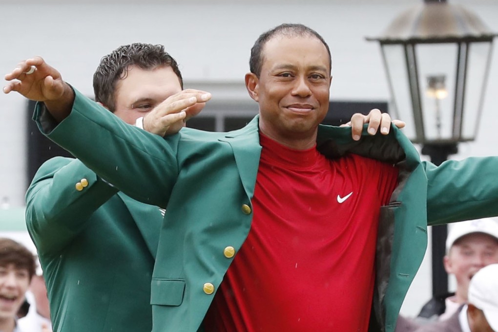 Tiger Woods is helped into his fifth green jacket by 2018 winner Patrick Reed. Photo: Kyodo