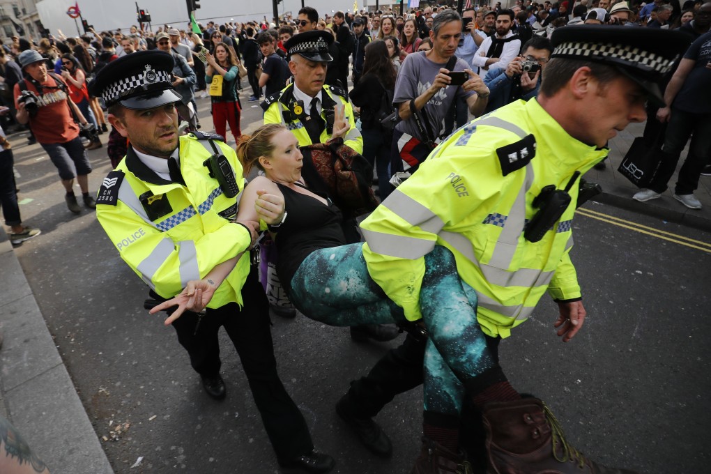 Police officers carry away a climate change activist who was blocking the road junction at Oxford Circus in central London on Thursday. Photo: AFP